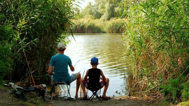 Dad and son fishing on lake. 
