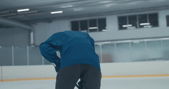 HANDHELD Caucasian male ice hockey player practicing skating drills at the training arena alone. 4K UHD