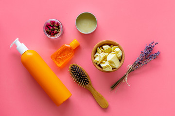 Cosmetics for hair care with jojoba, argan or coconut oil. Bottles and pieces of oil on pink background top view pattern