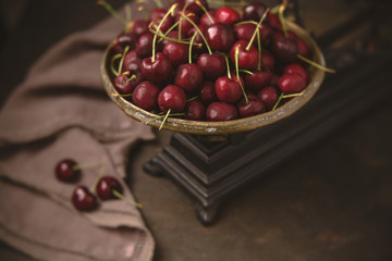 Freshly Picked Cherries in an Antique Scale on Warm Brown Background