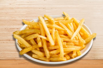Plate of french fries on wooden table