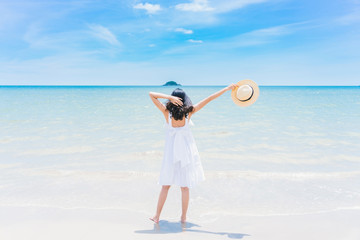 Back view of a happy traveller woman in white dress enjoys her tropical beach vacation, Vacation and traveling concept.