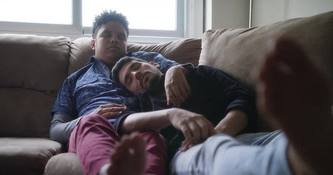 Young Gay Men Sleeping And Relaxing On Sofa At Home