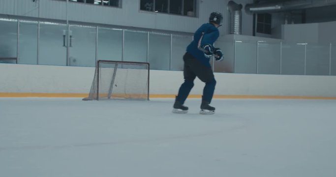 Caucasian male ice hockey player practicing slap shot at the training arena alone. 4K UHD