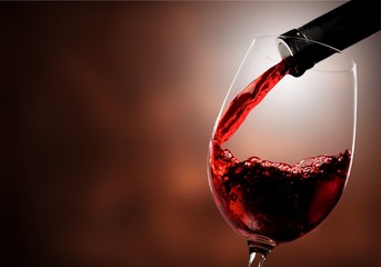 Red wine pouring in glass on  background - obrazy, fototapety, plakaty
