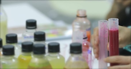 Close up scene VDO of someone hands pouring juice from one test tube to another one, concept for juice factory.
