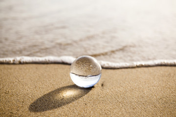 glass ball crystal clear reflecting the sea and beach in the morning