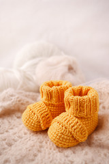 Fototapeta na wymiar Children's yellow knitted booties on a light gentle background. The concept of expecting a child, motherhood, parenthood, the idea of a gift for a newborn