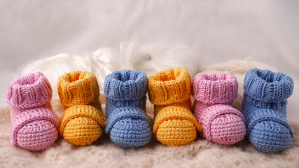 Fototapeta na wymiar pregnancy concept, Three pairs of baby booties on a light background