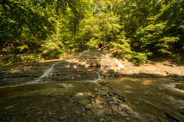 Naklejka na ściany i meble Small waterfall cascading on the creek
