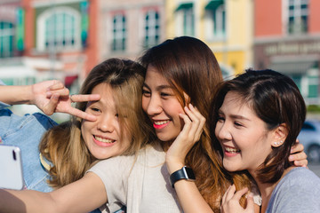 Obraz premium Attractive beautiful asian friends women using a smartphone. Happy young asian teenage at urban city while taking self portraits with her friends together with a smartphone.