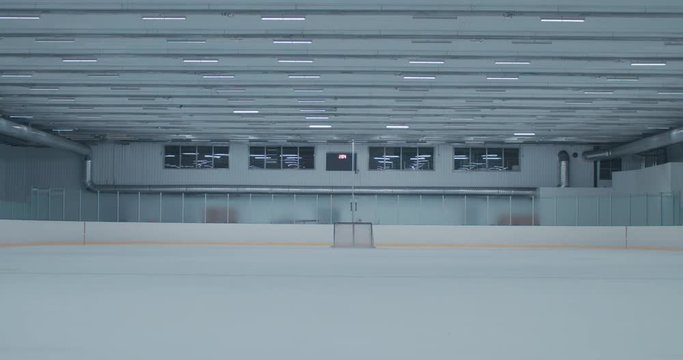 WIDE EST Lights are turning on on an empty ice hockey training rink, no players. 4K UHD