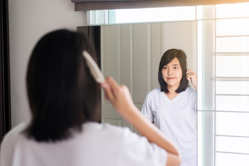 Fototapeta na wymiar Woman hand having combing her hair in bedroom mirror