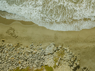 Aerial Top Down Drone View of Beach waves Writing in Sand