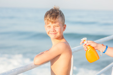 Mom apply sunscreen on the back of a child while traveling on a ship