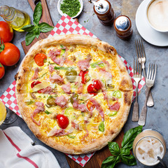 Breakfast pizza with scrambled egg, ham and tomatoes