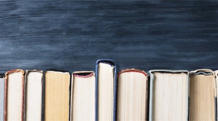 Ancient books in a row on wooden background