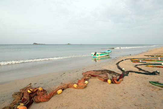 Fishing boat beached next to fishing nets with floats drying on Nilaveli beach in Trincomalee Sri Lanka Asia