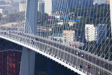 Fototapeta premium Golden cable-stayed bridge road car traffic from above. Modern Vladivostok Russia night illumination. Old and modern central buildings.