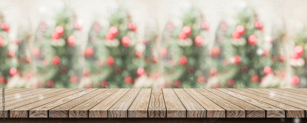 Poster Empty rustic wood plank table top with abstract blur christmas tree red decor ball and snow fall background with bokeh light,winter Holiday backdrop,Mock up banner for display of product or promotion.