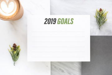 Top view of new year 2019 goals on white paper card and coffee cup on marble table office desk.resolutions for life.