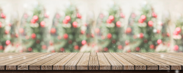 Empty rustic wood plank table top with abstract blur christmas tree red decor ball and snow fall...