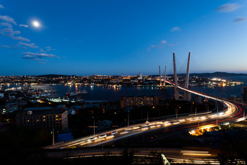 Fototapeta na wymiar Golden cable-stayed bridge road car traffic from above. Modern Vladivostok Russia night illumination. Old and modern central buildings.