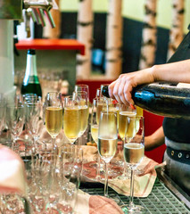 Bartender pouring champagne or spakling wine into glass, close-up in glasses in restaurant