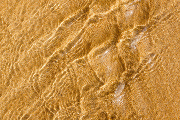 Golden sand under transparent sea water, abstraction, texture, background  of sand pattern on a beach in the summer closeup of sand under the water