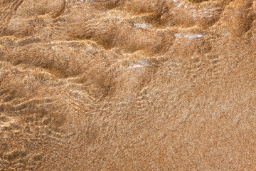 Golden sand under transparent sea water, abstraction, texture, background  of sand pattern on a beach in the summer closeup of sand under the water