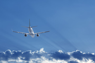 Airplane flying behind the clouds, back view