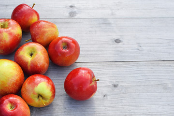 Red fresh shiny apples on grey weathered wooden table background with copy space for text. Freshly harvested sweet tasty fruit as healthy snack or prepare for delicious salad cooking or bakery.