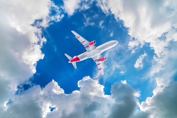 Airplane flying in the cloudy sky, bottom view