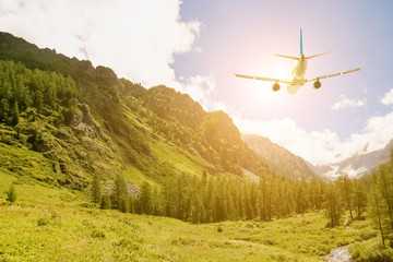 Fototapeta na wymiar Airplane flying over the green mountains