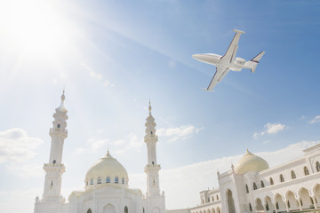 Airplane flying over beautiful white mosque