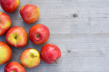 Red fresh shiny apples on grey weathered wooden table background with copy space for text. Freshly harvested sweet tasty fruit as healthy snack or prepare for delicious salad cooking or bakery.