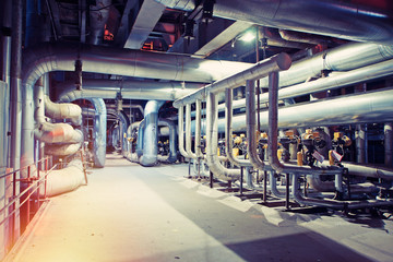 Equipment, cables and piping as found inside of a modern industrial power plant. Industrial zone, Steel pipelines, valves, cables and walkways
