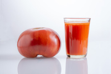 Large tomato and a glass of tomato juice