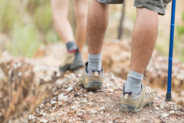 Group of man and women during hiking excursion in woods, walking in a queue along a path. Low section view