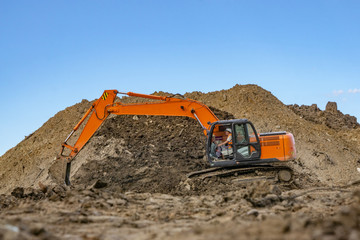 Excavator at the construction site pours a pile of soil