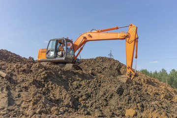 Obraz premium Orange excavator loads the land on a construction site..
