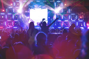 Audience with hands raised at a music festival and lights