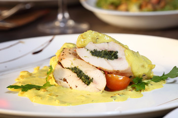 Stuffed cream cheese chicken roll with sauce on a plate. Chicken breasts filled and rolled up with a cream cheese and baked in the oven.