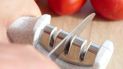 Manual sharpening of a knife in a special sharpener in a kitchen