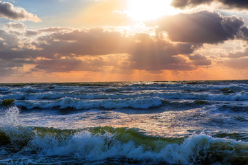 sunset in the cloudy sky over the stormy sea