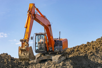 Orange excavator loads the land on a construction site..