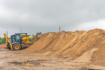 Bulldozer at a construction site forms a pile of sand
