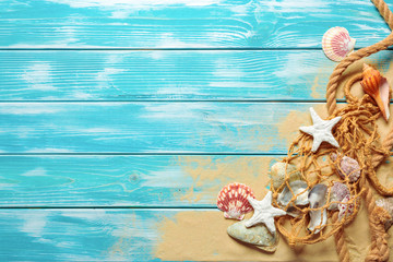 sea rope with many different sea shells on the sea sand on a blue wooden background. Top view