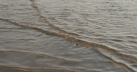 closeup of small waves on a beach at sunset