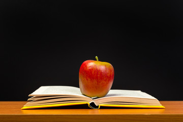 red apple and old books on wooden tabletop